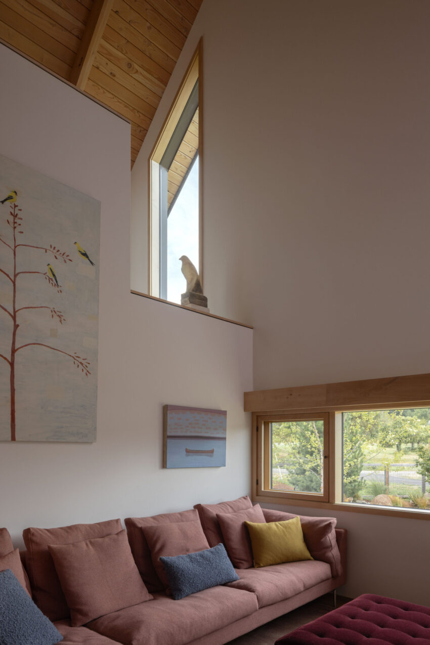 Dyes Inlet House — Phòng khách với sofa và tranh, cửa sổ mở ra vườn.
