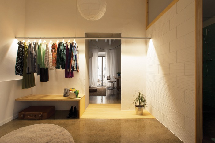 Khu vực ban đêm - căn hộ 1 - với thảm trải trên sàn gỗ để ngủ, thanh treo quần áo thay cho tủ đựng