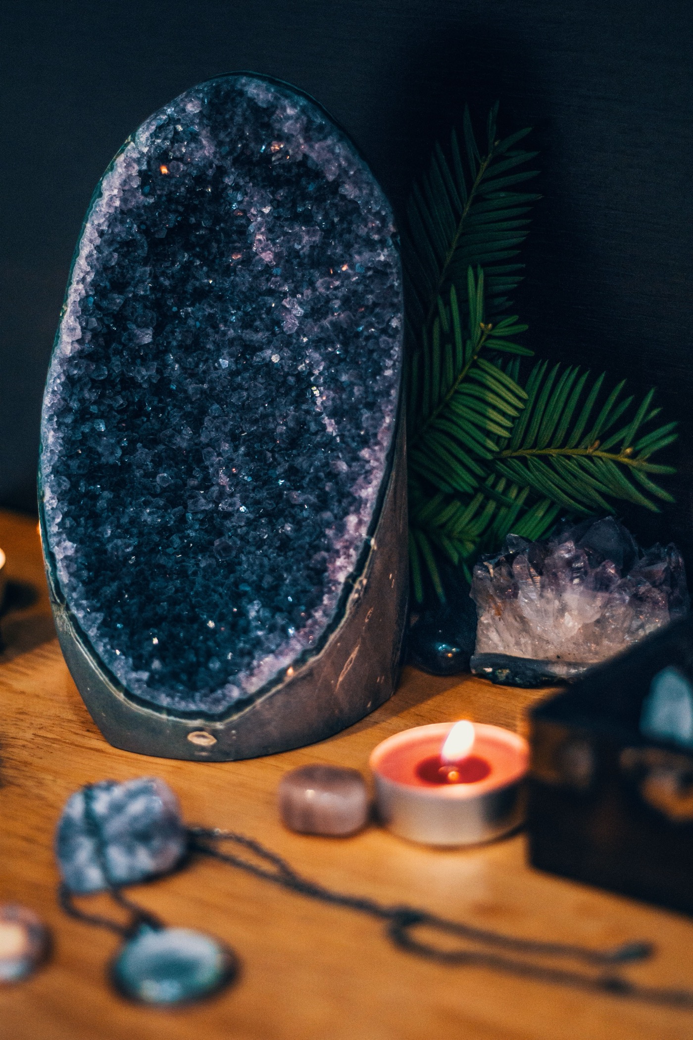 Geode thạch anh tím, nến và cây xanh trên bàn