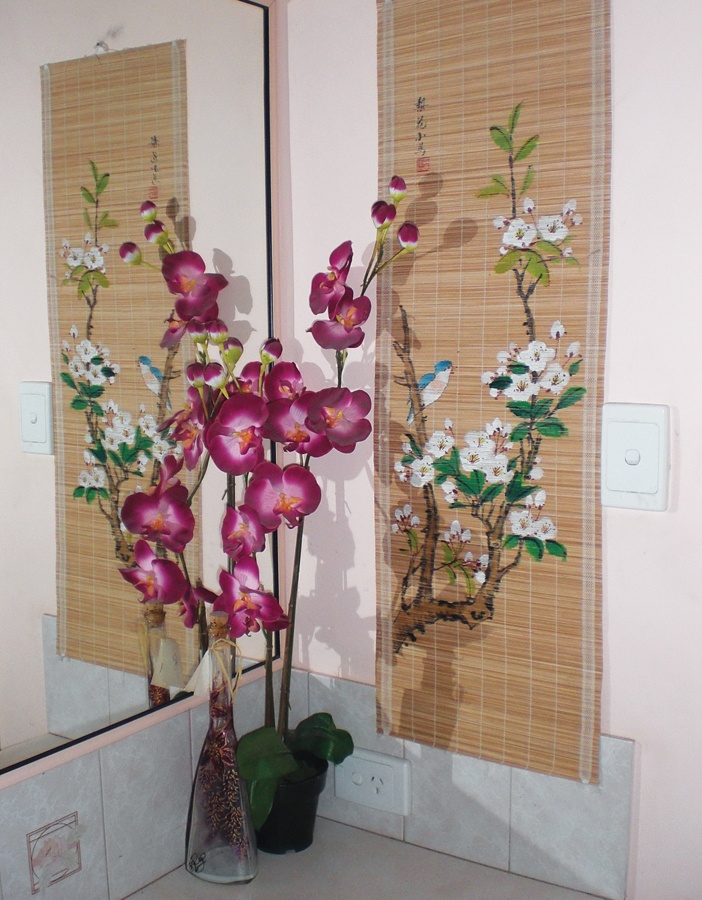 Một nhánh phong lan và bức tranh hoa trên phên tre ở phòng tắm 