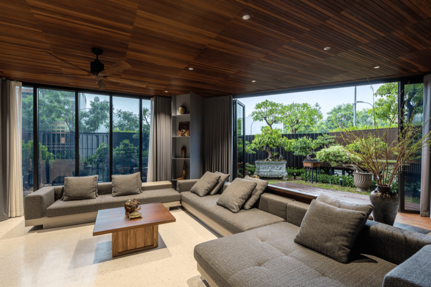 Phòng khách trần gỗ sẫm mở ba mặt kính ra vườn