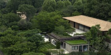 Nhìn từ trên cao, nhà mái ngói dài nằm lọt giữa tán rừng ở Jardim GMM