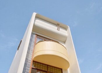 Mặt tiền nhà chị Châu với ban công cong màu vàng bơ và mảng gạch kính