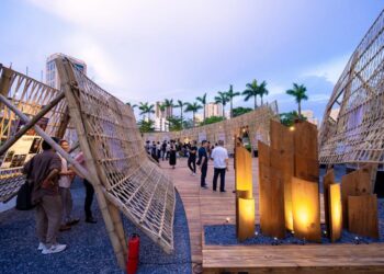 Lễ vinh danh Top 10 Awards 2025 và Khai mạc Pavilion “Dong buồm” Chiều ngày 22/5/2026, Bảo tàng Hà Nội trở thành điểm hẹn của giới kiến trúc và thiết kế khi Lễ vinh danh Top 10 Awards 2025 cùng triển lãm Pavilion “Dong buồm” chính thức khai mạc. Sự kiện thu hút đông đảo kiến trúc sư, chuyên gia, doanh nghiệp và cộng đồng yêu kiến trúc trên cả nước. Không chỉ là lễ trao giải thường niên, Top 10 Awards 2025 còn mở ra một không gian trải nghiệm sáng tạo. Tại đây, công chúng có cơ hội tiếp cận gần hơn với kiến trúc đương đại Việt Nam qua các công trình tiêu biểu và triển lãm tương tác mở. Pavilion “Dong buồm” tạo dấu ấn tại Bảo tàng Hà Nội Mở đầu chương trình là nghi thức khai mạc Pavilion “Dong buồm”. Công trình do Dplus Vietnam thiết kế và thực hiện. TS.KTS Phan Đăng Sơn, Chủ tịch Hội Kiến trúc sư Việt Nam, cho biết nhiều công trình nhà ở mang bản sắc địa phương của Việt Nam đã đạt giải thưởng quốc tế trong thời gian gần đây. Theo ông, Top 10 Awards ngày càng định hình rõ theo hướng bền vững và chú trọng kiến trúc xanh. Lấy cảm hứng từ hình tượng cánh buồm căng gió, Pavilion mang thông điệp về hành trình vươn xa của kiến trúc Việt trong thời kỳ hội nhập. Không gian triển lãm được tổ chức theo cấu trúc hướng tâm. Trung tâm là “Lõi Di sản”, nơi lan tỏa ba giá trị cốt lõi gồm bản địa, đổi mới và nhân văn. Hệ kết cấu tre đan cùng các lớp vách kiến trúc tạo nên cảm giác chuyển động liên tục. Đồng thời, vật liệu truyền thống được kết hợp với trải nghiệm mở để tăng tính kết nối với công chúng. Không gian triển lãm đưa kiến trúc đến gần công chúng Theo KTS Phương Đoàn, đại diện Dplus Vietnam, Pavilion “Dong buồm” không chỉ là nơi trưng bày mà còn là biểu tượng thị giác cho tinh thần kiến trúc Việt Nam đương đại. Thông qua vật liệu tre đan và không gian mở, nhóm thiết kế mong muốn tạo nên trải nghiệm gần gũi hơn giữa kiến trúc với đời sống thường nhật. Điểm đáng chú ý của triển lãm năm nay là khả năng tương tác cao. Người tham dự không chỉ quan sát công trình đạt giải mà còn được trải nghiệm bằng thị giác, cảm xúc và các cuộc đối thoại mở về kiến trúc Việt Nam hiện đại. Vinh danh 30 công trình tiêu biểu của Top 10 Awards 2025 Sau phần khai mạc triển lãm là lễ vinh danh 30 công trình xuất sắc nhất thuộc ba hạng mục gồm Top 10 Houses, Top 10 Interior Designs và Top 10 Green Projects. Top 10 Awards được khởi xướng từ năm 2018 bởi KIENVIET MEDIA. Đến nay, giải thưởng đã trở thành một trong những hệ quy chiếu chuyên môn uy tín của ngành kiến trúc và nội thất Việt Nam. Mùa giải 2025 ghi nhận 363 đồ án tham dự trên toàn quốc. Các công trình đều trải qua quá trình đánh giá độc lập từ Hội đồng Giám khảo chuyên môn. Nhiều dự án nhà ở gây ấn tượng nhờ khả năng kết nối giữa kiến trúc với văn hóa địa phương. Trong khi đó, các công trình xanh tiếp tục chú trọng giải pháp sinh thái, vật liệu tái chế và đa dạng sinh học. Top 10 Awards mở rộng hạng mục từ năm 2026 Tại sự kiện, Ban Tổ chức công bố kế hoạch bổ sung hai hạng mục mới gồm Top 10 Social Housing và Top 10 C-Solutions từ mùa giải 2026. Theo KTS Vương Đạo Hoàng, Trưởng Ban Tổ chức, định hướng mới nhằm cập nhật những vấn đề quan trọng của ngành kiến trúc hiện nay. Trong đó có bài toán nhà ở cho số đông và nhu cầu phát triển giải pháp công nghệ bền vững. Đây được xem là bước mở rộng quan trọng của Top 10 Awards trong hành trình thúc đẩy kiến trúc gắn với giá trị xã hội và phát triển dài hạn. Kiến trúc Việt Nam hướng tới hành trình hội nhập quốc tế Thông qua Pavilion “Dong buồm”, Top 10 Awards 2025 tiếp tục khẳng định vai trò kết nối cộng đồng sáng tạo trong nước. Đồng thời, chương trình cũng góp phần lan tỏa tinh thần kiến trúc Việt ra quốc tế. Triển lãm Top 10 Pavilion “Dong buồm” hiện mở cửa tự do tại Bảo tàng Hà Nội đến hết ngày 31/9/2026. Đây là cơ hội để công chúng khám phá những xu hướng nổi bật của kiến trúc Việt Nam hiện đại, từ kiến trúc xanh đến không gian sống giàu bản sắc. Trong bối cảnh ngành kiến trúc ngày càng đề cao tính bền vững và trải nghiệm con người, Top 10 Awards đang trở thành động lực thúc đẩy thế hệ kiến trúc sư Việt tự tin sáng tạo và hội nhập sâu hơn với thế giới - 4