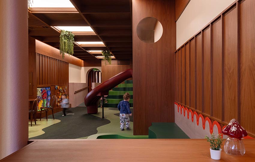 Không gian nội thất gỗ walnut tại Willow Play Cafe ở Toronto với cầu trượt đỏ và khu vui chơi tích hợp cạnh khu cà phê - 11